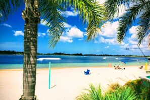 A beach scene with clear blue water, a sandy shore, and palm trees. - Peaceful and Private New House with Hot Tub/ Fire Pit (Spring Hill)