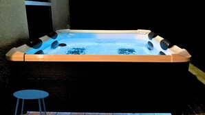 A hot tub with a wooden deck and a blue stool. - Peaceful and Private New House with Hot Tub/ Fire Pit (Spring Hill)