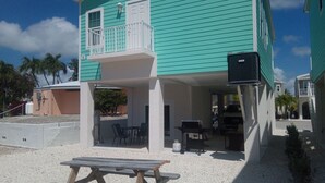 A turquoise building with a covered patio, outdoor seating, and a barbecue area. - New Construction in Venture Out! 3 night minimum stay. (Cudjoe Key)