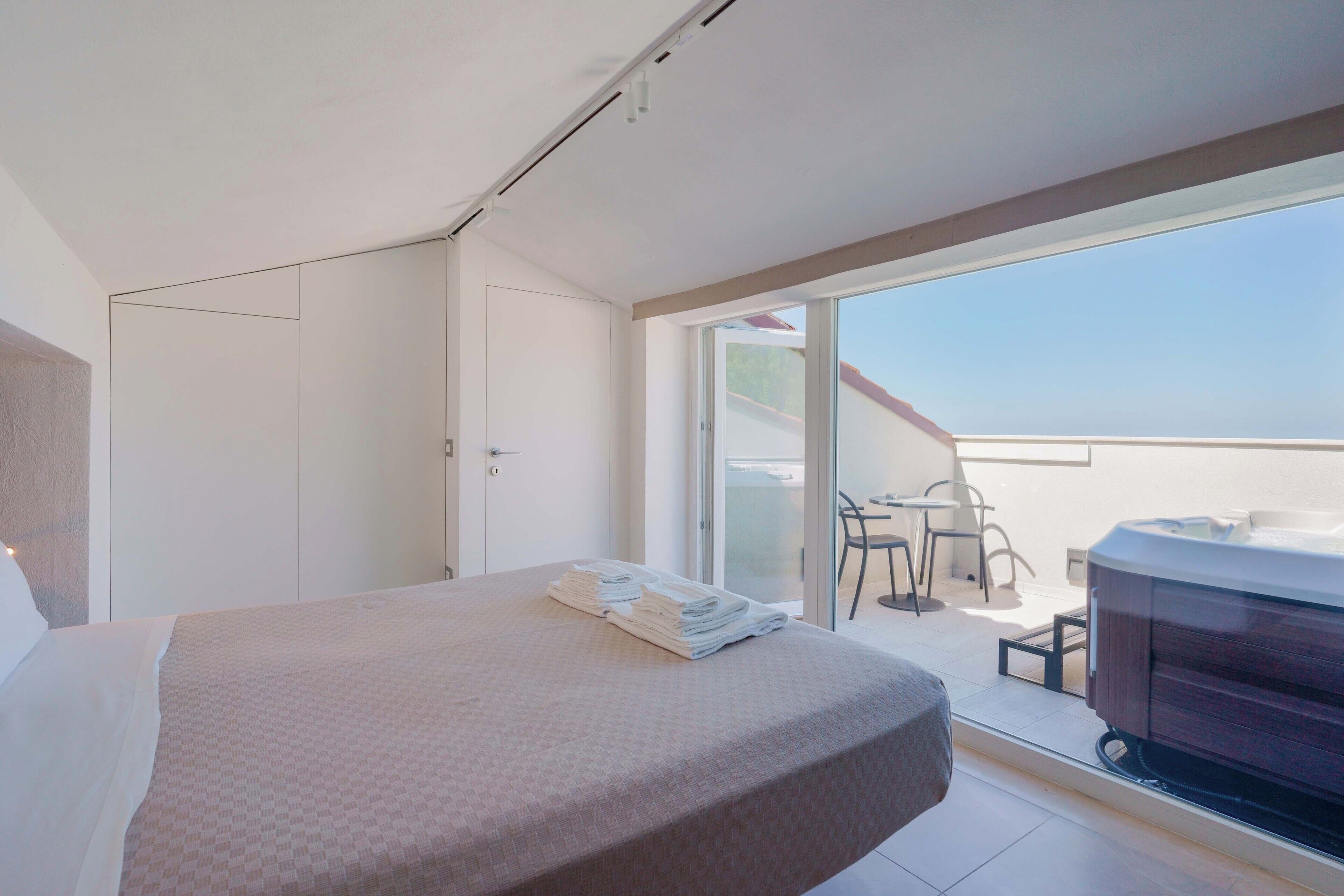 Et hotelværelse med seng, badeværelse og balkon med bord og stole.