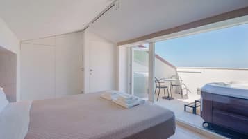 Et hotelværelse med seng, badeværelse og balkon med bord og stole.