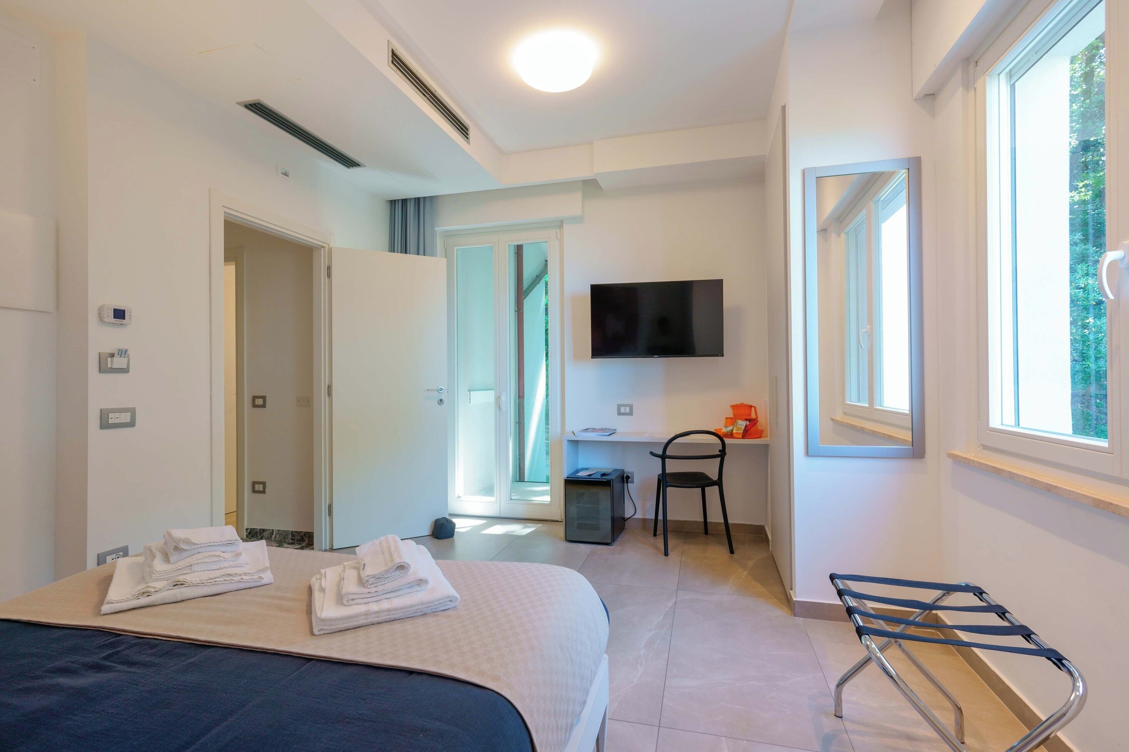Een hotelkamer met een bed, een televisie, een bureau, een stoel en een raam.