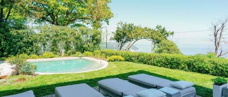 Zona de piscina con sillones y vistas al mar.