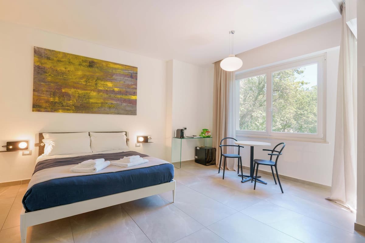 A modern bedroom with a bed, bedside lamps, a desk, and a chair.