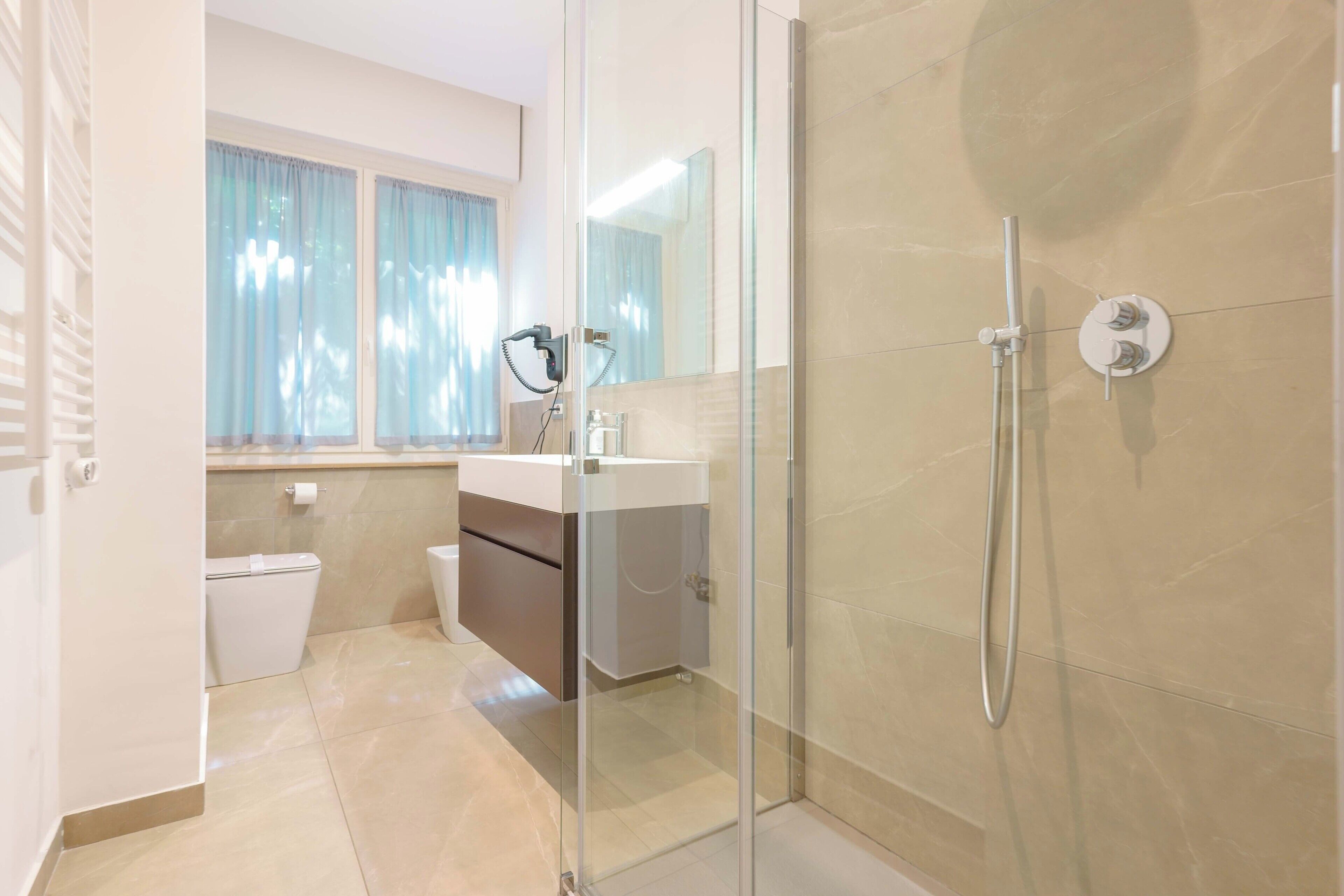 A modern bathroom with a glass shower enclosure, a toilet, and a sink with a mirror.