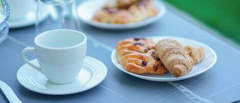 Een tafel met een witte kop, een bord croissants en een glas water.