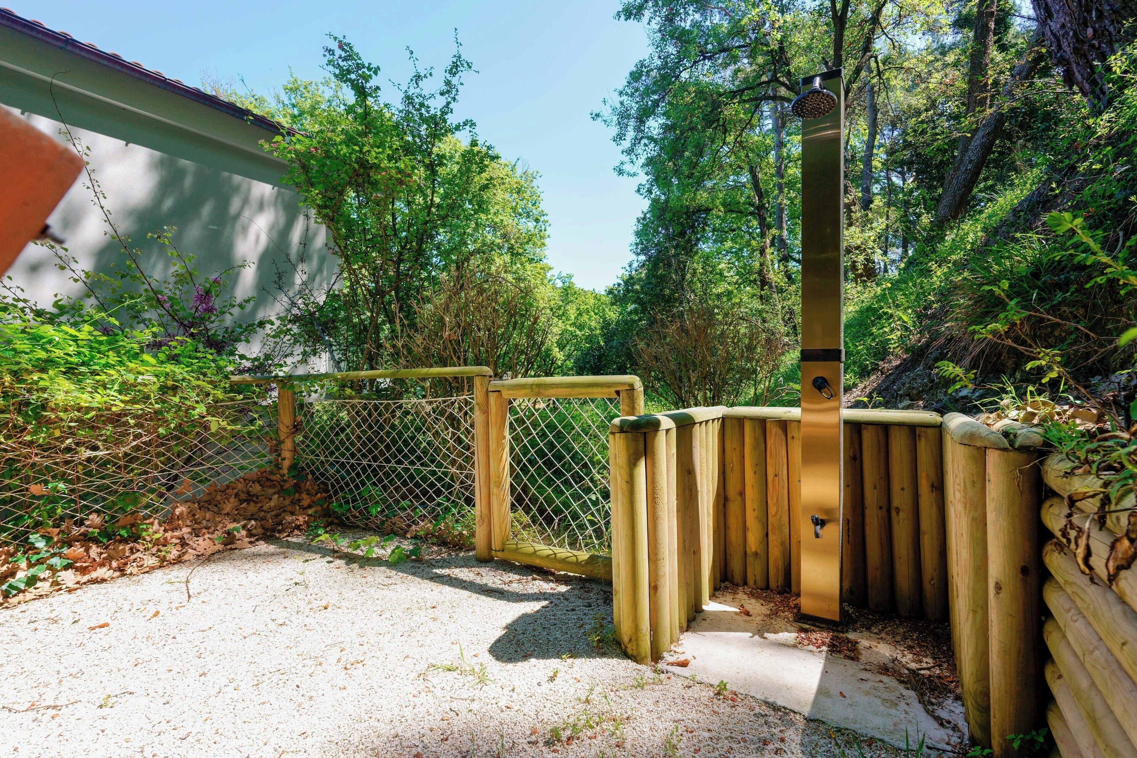 Une clôture en bois, un portail en métal et un chemin en béton dans un espace jardin.