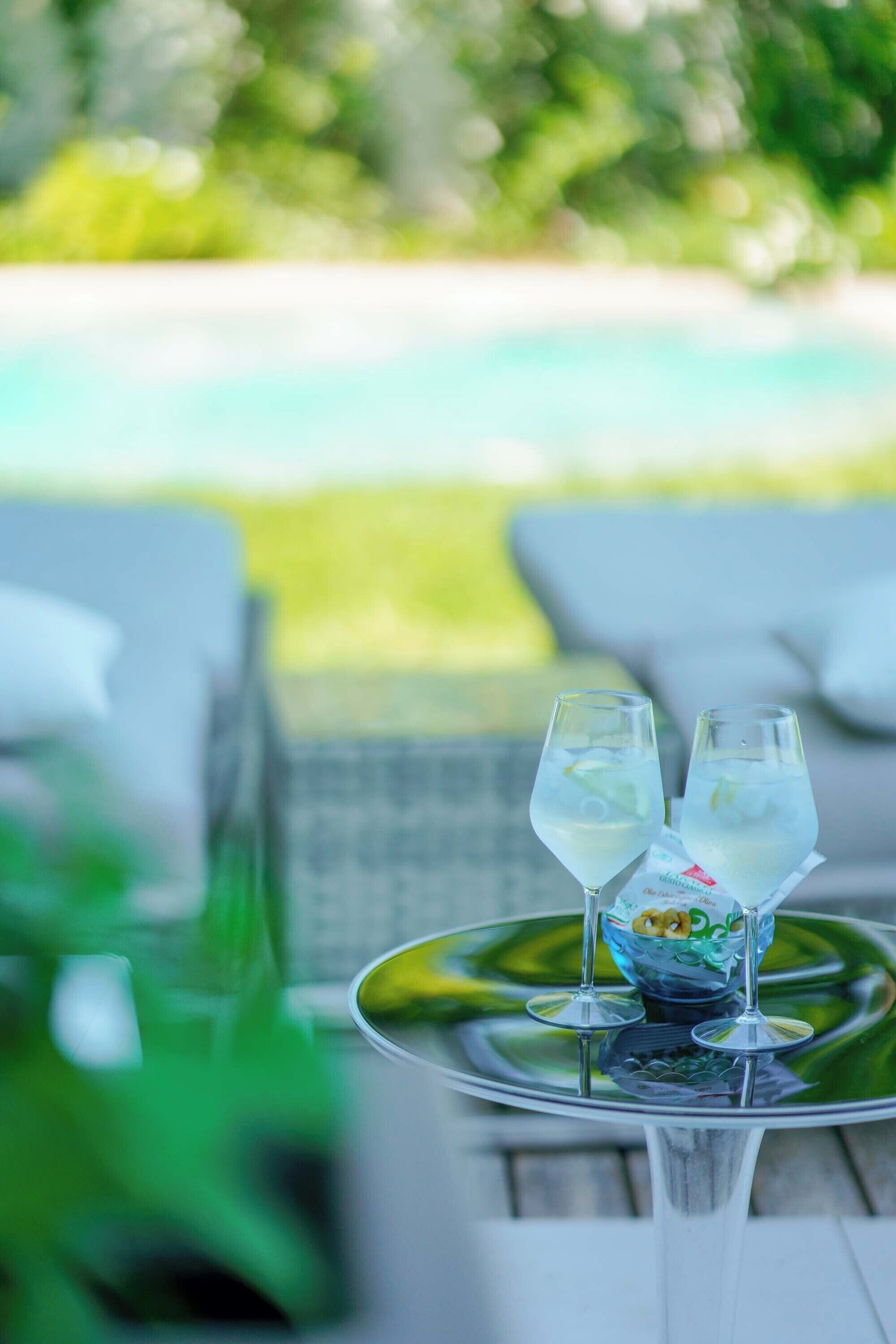 Una mesa con dos vasos de una bebida transparente, un cuenco decorativo y una hoja verde.