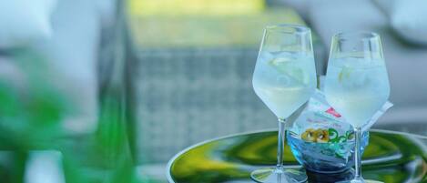 Una mesa con dos vasos de una bebida transparente, un cuenco decorativo y una hoja verde.
