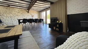 Ein großzügiger Wohnbereich mit Steinwand, Holzboden und Kamin.