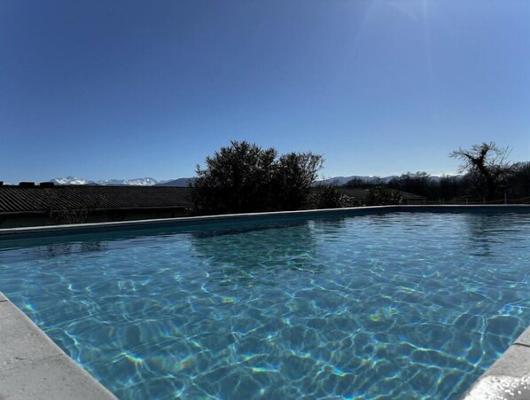 A clear swimming pool with a view of mountains in the background.