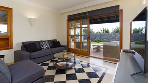 A living room with a checkered floor, a sofa, a coffee table, and a TV. - Beautiful 3 Bedroom Detached Villa, Sea View,Private Garden, Heated Pool, Aircon (Yaiza)