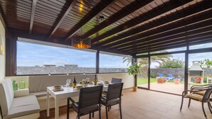 A dining area with a table set for four, a bench, and a view of the outdoors. - Beautiful 3 Bedroom Detached Villa, Sea View,Private Garden, Heated Pool, Aircon (Yaiza)