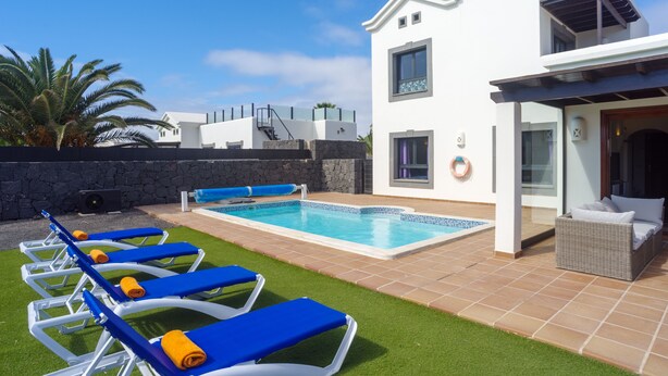 A modern pool area with lounge chairs and a clear blue pool. - Beautiful 3 Bedroom Detached Villa, Sea View,Private Garden, Heated Pool, Aircon (Yaiza)