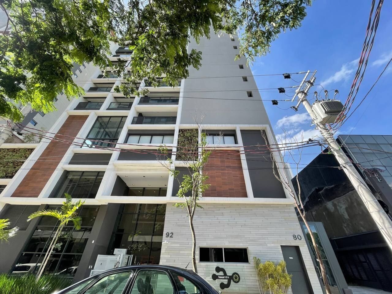 Un edificio moderno de varios pisos con una combinación de paneles de vidrio y madera, con los números 92 y 80.