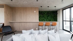 A modern interior with a seating area, a wooden panel wall, and a green wall with plants. - Haus Residence Brooklin (São Paulo)
