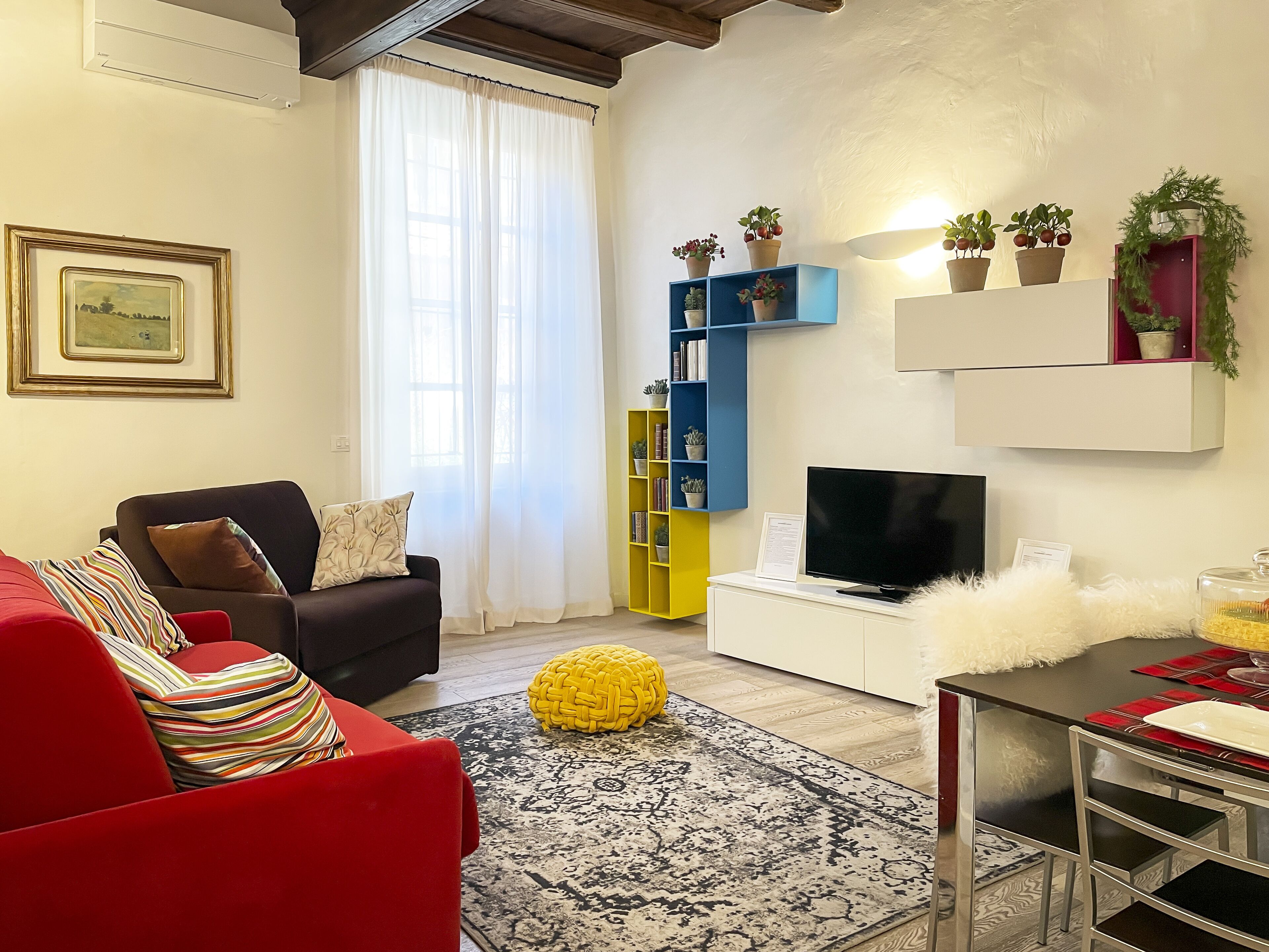 A living room with a sofa, a television, a coffee table, a rug, and a bookshelf.