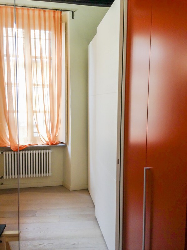 A room with a radiator, a window with sheer curtains, and a closed door. - LuxRent Apartment Castello (Turin)
