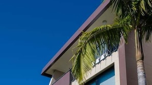 Ein modernes, zweistöckiges Gebäude mit Balkon und einer Palme im Vordergrund.