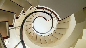 Eine Wendeltreppe mit einer offenen Mitte, umgeben von Wänden und Geländern.