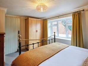 A bedroom with a bed, a wooden wardrobe, a window with curtains, and a ceiling light fixture. - 2 bedroom accommodation in Barnard Castle (Barnard Castle)