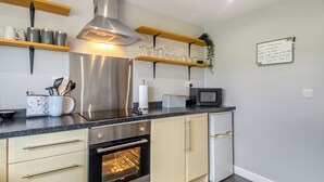 Une cuisine moderne dotée d’appareils électroménagers en acier inoxydable, d’étagères en bois et d’un tableau blanc où sont affichées des notes.
