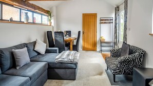 Un salon moderne avec un canapé, des fauteuils, une porte en bois et une vue par la fenêtre.