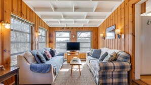 A cozy living room with wooden walls, a large TV, two sofas, and a coffee table. - 1 Mi to Beach! Family Gloucester Gem w/ Yard (Gloucester)
