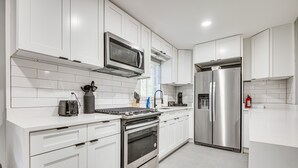 A modern kitchen with white cabinetry, stainless steel appliances, and a tiled backsplash. - Cocoa Home w/ Large Yard: 3 Mi to Indian River! (Cocoa)