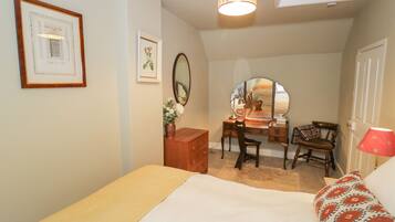 Een slaapkamer met een bed, een bureau, een stoel, een spiegel, een dressoir en een lamp.