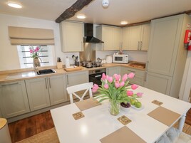 A modern kitchen with light-colored cabinets, a central island with a vase of pink tulips, and a microwave on the countertop.