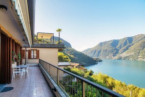 Un balcón con una mesa y sillas, con vistas a un lago y montañas.