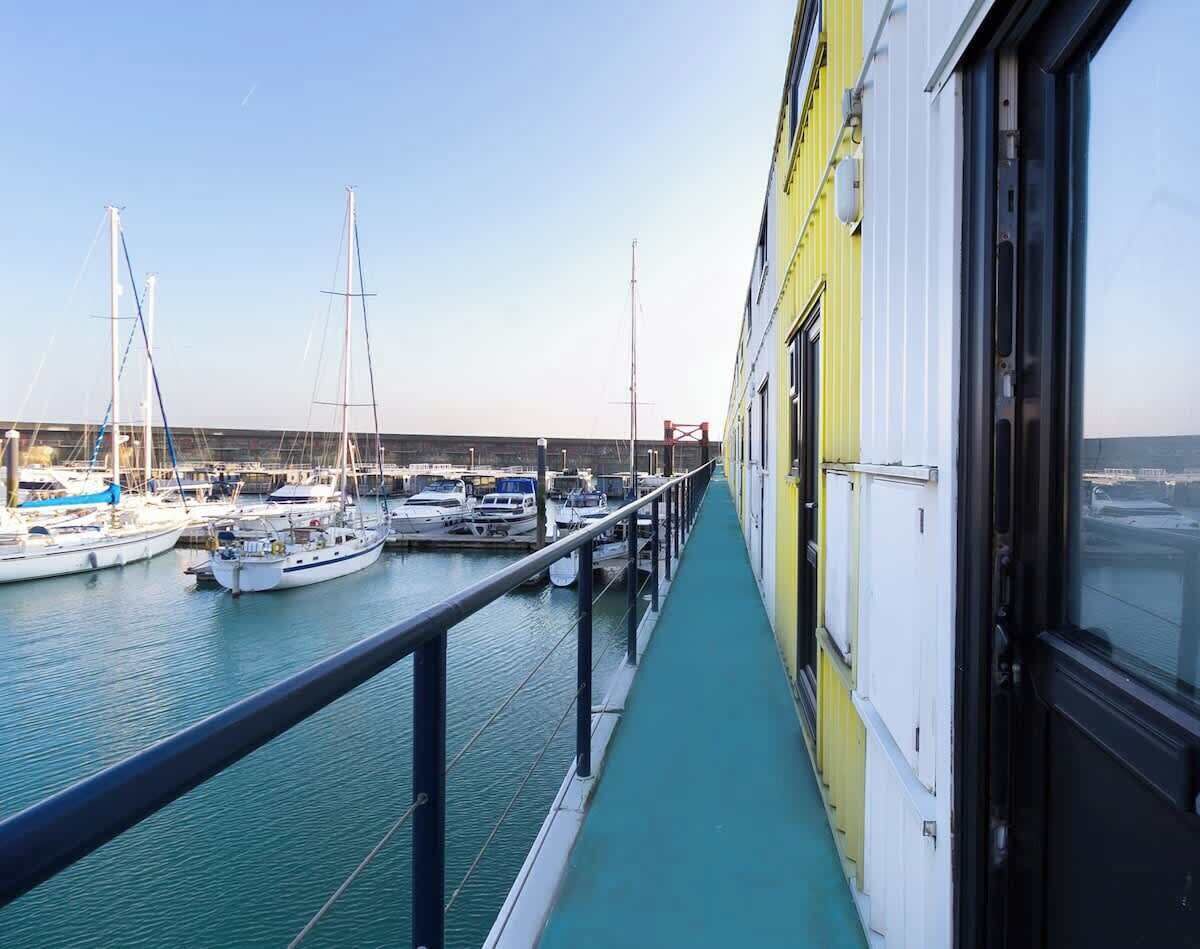 Een balkon met uitzicht op een jachthaven, waar verschillende boten liggen aangemeerd.