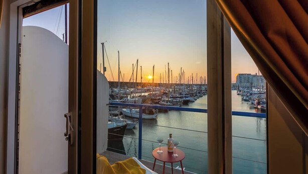Un balcon donnant sur une marina au coucher du soleil.