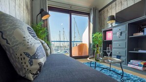 A modern living room with a sofa, a glass table with wine glasses, and a bookshelf. - Harbour Hideaway - Free Parking (Brighton and Hove)