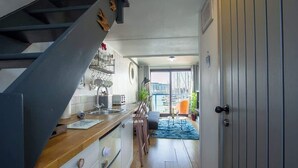 A modern kitchen with a wooden countertop, a built-in oven, and a staircase leading to another level. - Harbour Hideaway - Free Parking (Brighton and Hove)