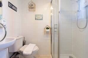 Une salle de bain moderne avec des toilettes, un lavabo et une douche. On y trouve des éléments de décoration, notamment un panneau indiquant « On se détend » et un autre panneau indiquant « Coin beauté ».