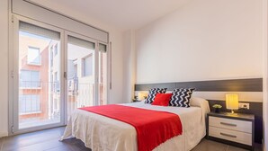 A bedroom with a large bed, a nightstand, a lamp, and a view through a sliding door to an outdoor area. - Nice apartment for 6 people with WIFI, A/C, TV, terrace and pets allowed (L'ampolla)