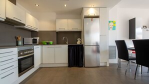 A modern kitchen with white cabinets, a stainless steel refrigerator, a microwave, and a stove. - Nice apartment for 6 people with WIFI, A/C, TV, terrace and pets allowed (L'ampolla)