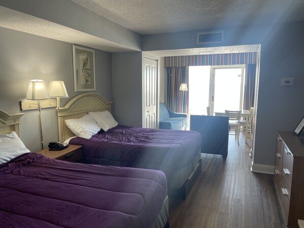 Une chambre d’hôtel avec deux lits, un bureau, une chaise et une vue sur l’extérieur.