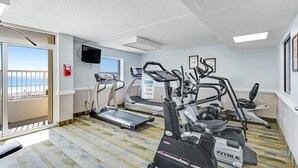 A fitness room with treadmills, elliptical machines, and a TV screen. - Oceanfront 2Qn Studio. Resort w/Lazy River, Pools (Myrtle Beach)