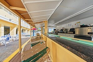 Ein Deckbereich mit Sitzgelegenheiten im Freien, einem Pool und einer Küchenzeile mit Kaffeemaschine.