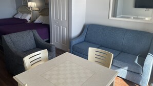 Une chambre d’hôtel avec un lit, un canapé, une table et un téléviseur.