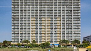 Un hôtel de grande hauteur doté de nombreux balcons, d’un toit plat et situé en bord de mer.