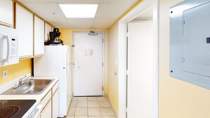 A narrow hallway with a kitchen area on one side, including a refrigerator, coffee maker, and sink. - Oceanfront 2Qn Studio. Resort w/Lazy River, Pools (Myrtle Beach)