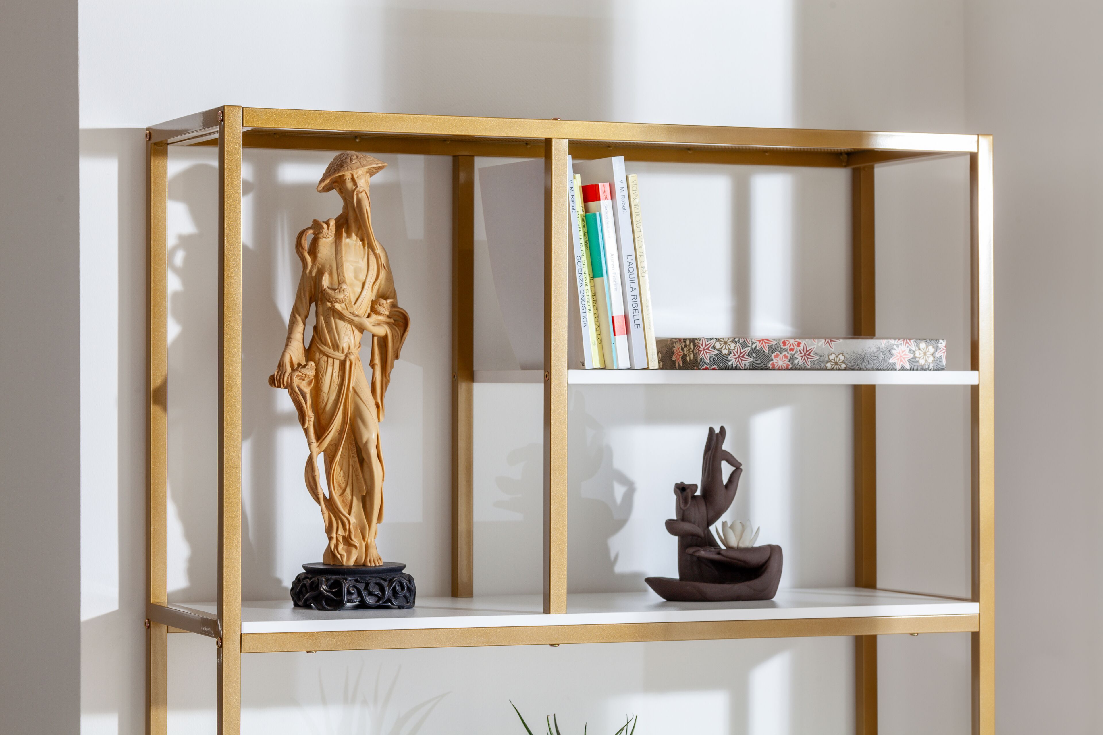 A bookshelf with a statue, books, and a small sculpture.