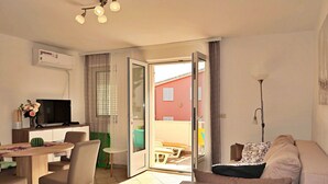 Un salon moderne comprenant un canapé, un téléviseur et un coin repas avec des chaises et une table.