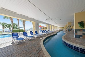 A pool area with lounge chairs and a view of the beach.