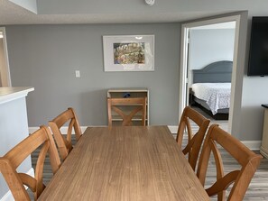 A dining area with a wooden table and chairs, a small side table, and a framed picture on the wall. - Oceanfront 3BR/2BA - Lazy River and Pools Resort (Myrtle Beach)