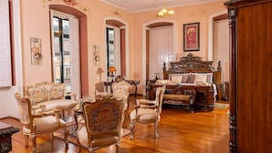 A room with ornate furniture, including a large bed with a wooden headboard, several upholstered chairs, and a table with a lamp. - Casa Colonial Quito (Quito)